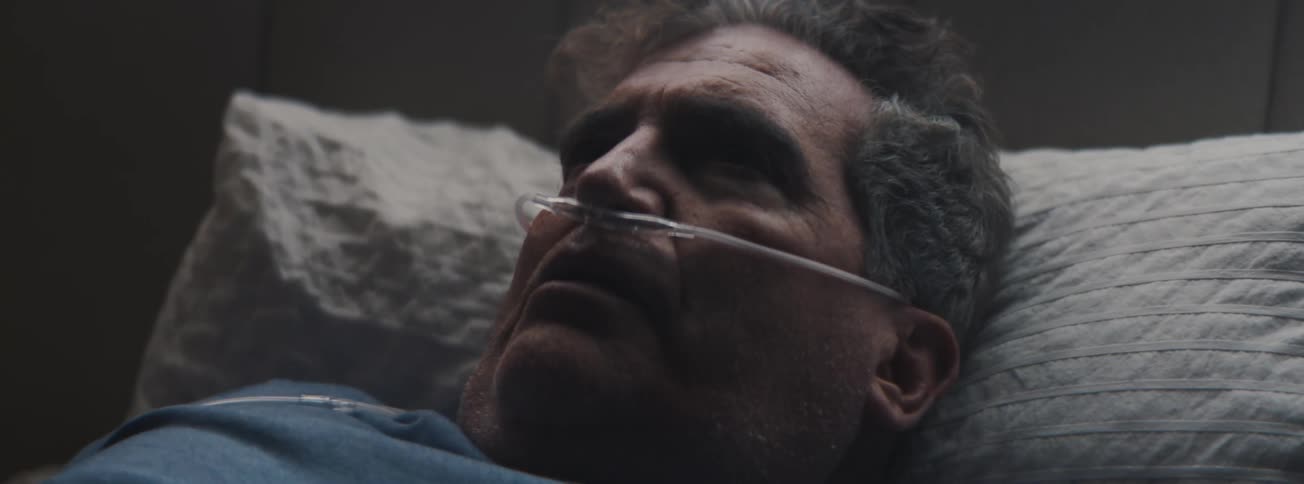 Senior man with a nasal canula wakes and rises from the pillow