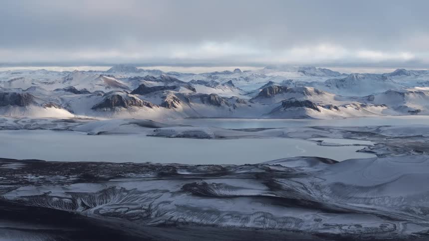 An aerial view of a region with snowy mountains and lakes