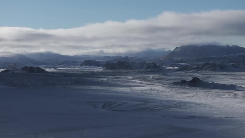 Aerial of plain and mountains covered by ice and snow