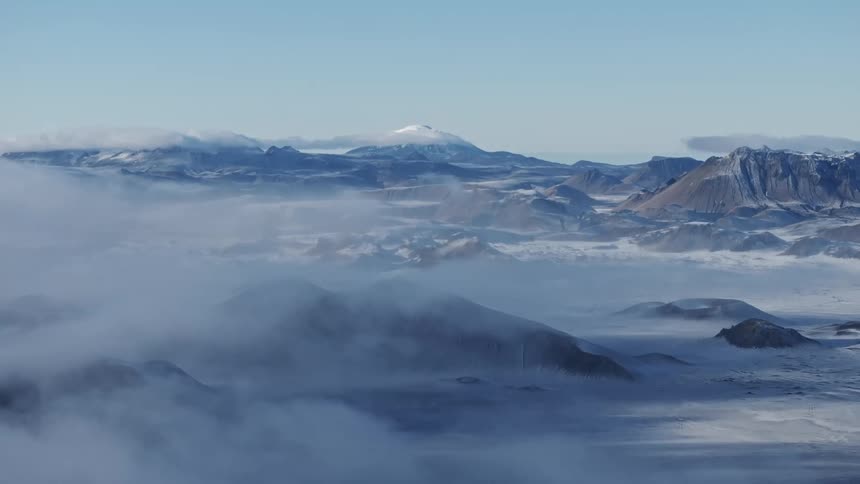 Aerial view of clouds over the mountains in a snowy landscape