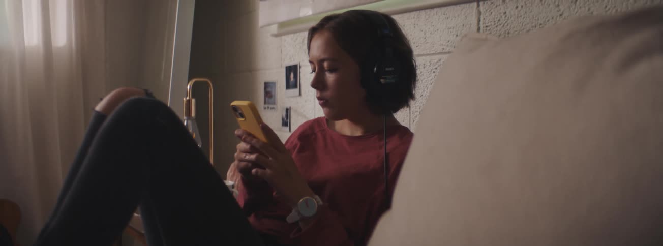 Young woman wearing headphones texting on her phone