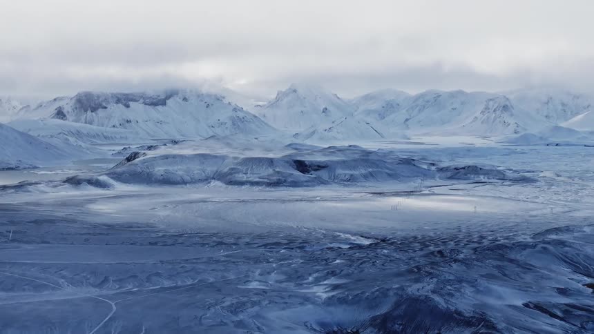 Aerial of snowcovered plain and mountains during winter