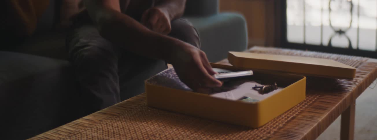Man sitting opening a memory box and taking out a frame with a photo