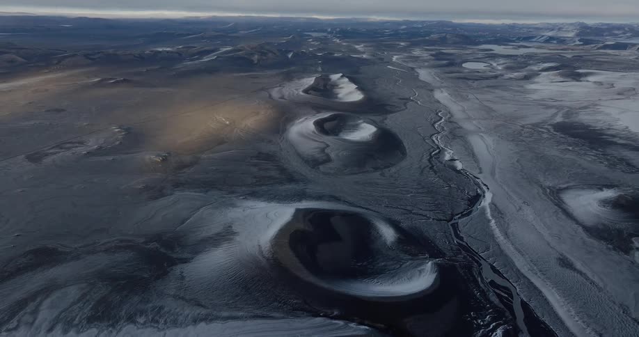 An aerial view of a region with mountains and snow on the ground