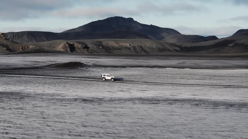 Aerial view of a white jeep driving in the tundra