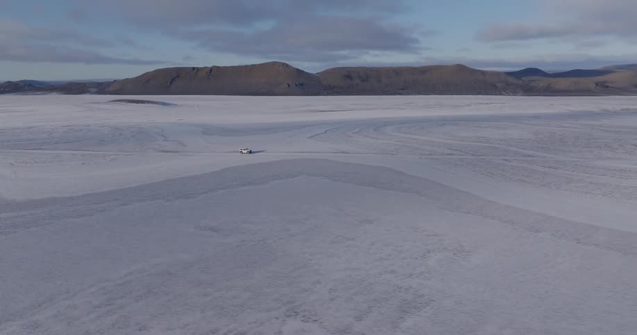 A car driving on a white desert road during the day