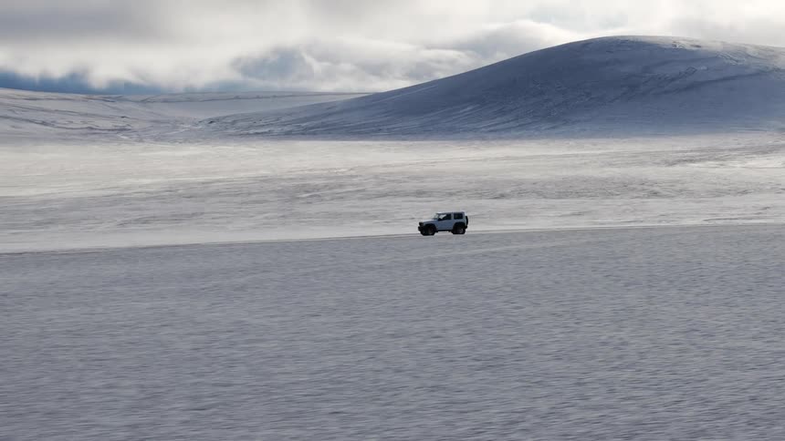 A white jeep moving on a desert road during the day