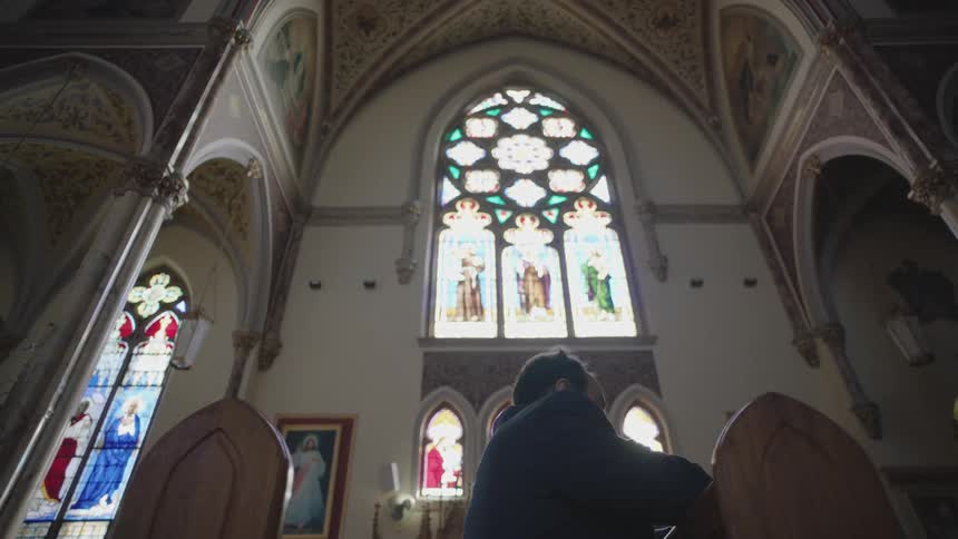 A man praying in a church during the day