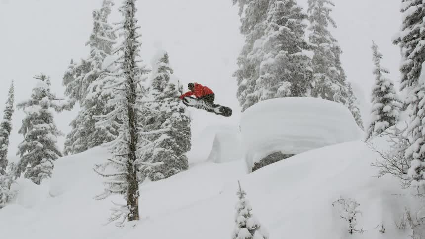 A snowboarder does a method over pillows into powder