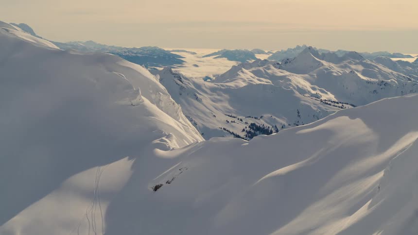 Aerial view of a forest in a valley between mountains in a snowy landscape