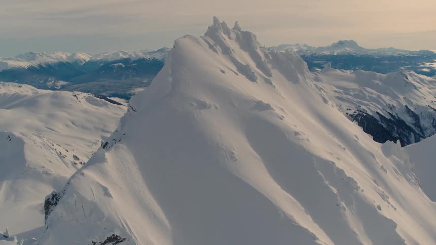 Aerial of a frozen mountain peak in winter at sunset