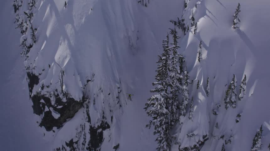 Aerial of snowboarder riding steep spines in powder
