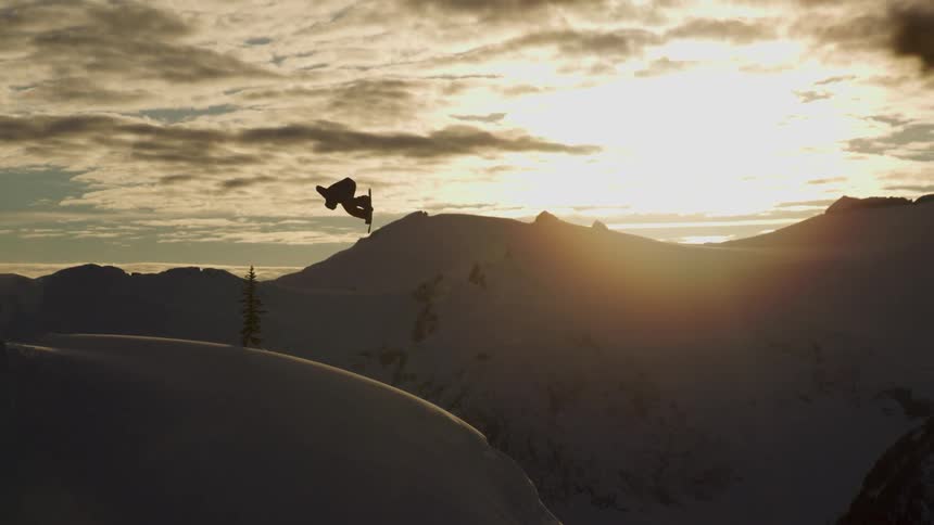 A snowboarder jumps as the sun sets