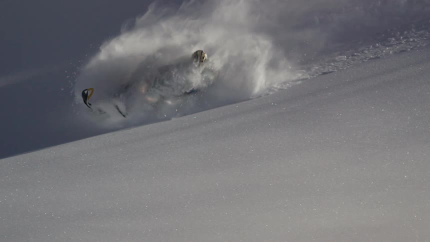 A man is riding his snowmobile carves deep snow