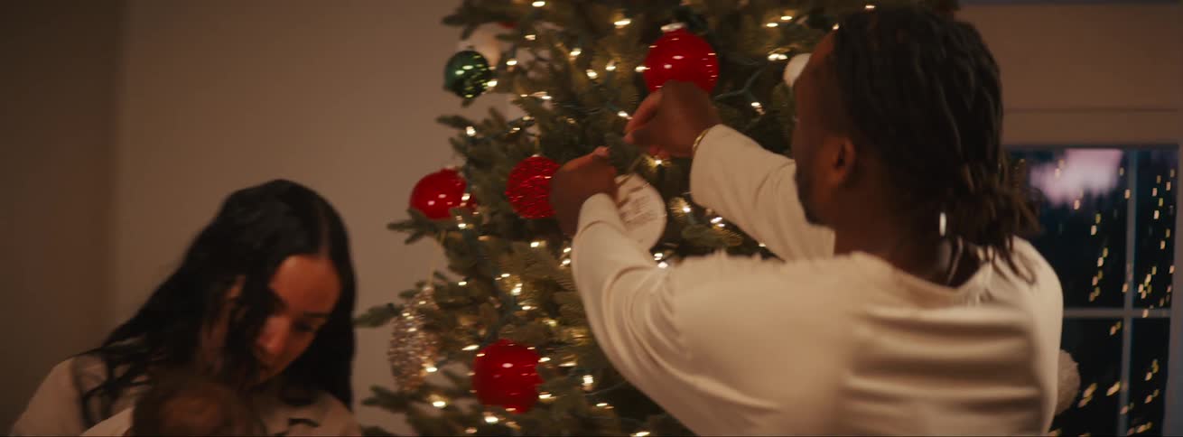 Parents decorating a christmas tree with their children around