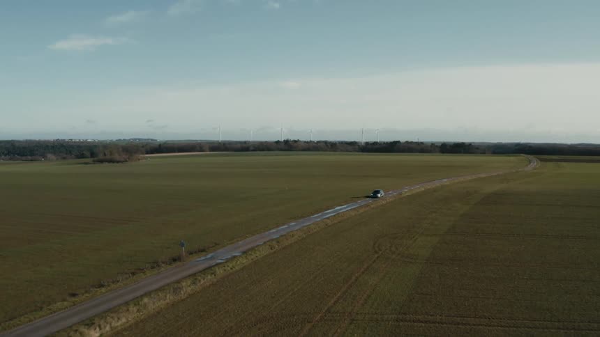 Aerial panorama of a highway with a car passing through a meadow