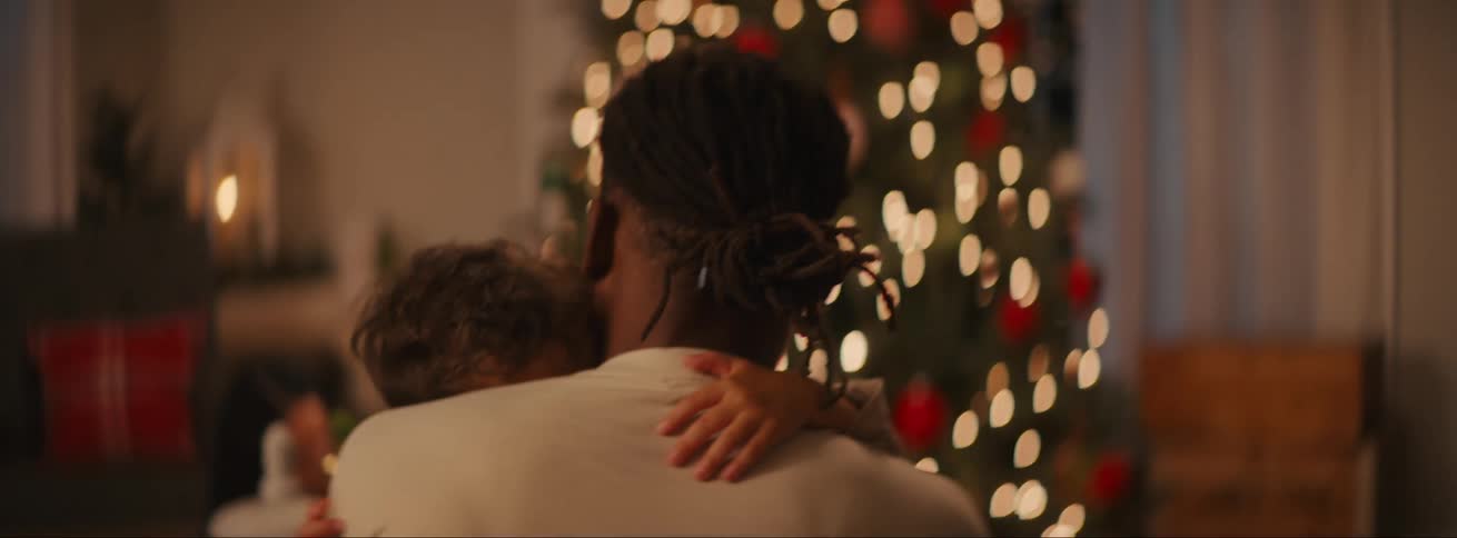 Father sitting with his son on his lap and getting up from the room while gently stroking his hair