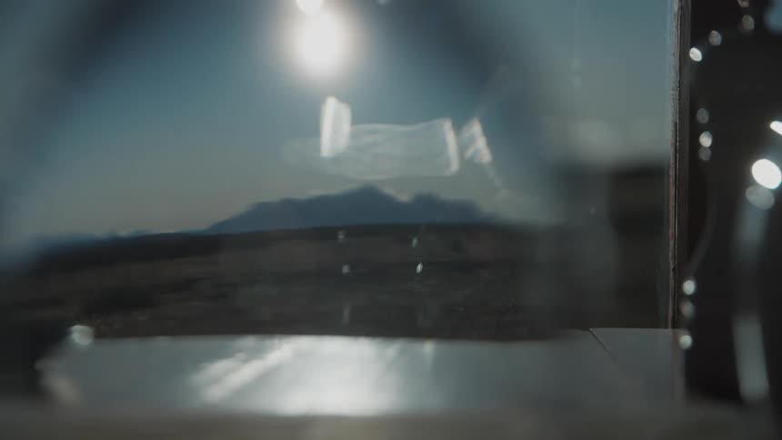 Glass being placed on the table bringing the mountains on the horizon into focus