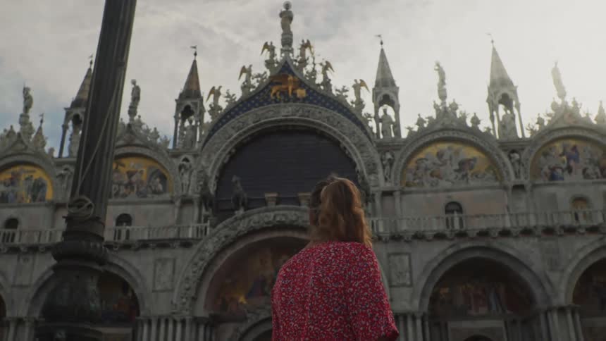Woman from behind observing the external architecture of a church