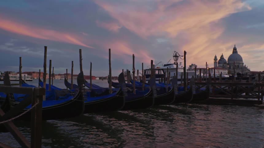 Blue canoes docked at a pier with a reddish dawn sky