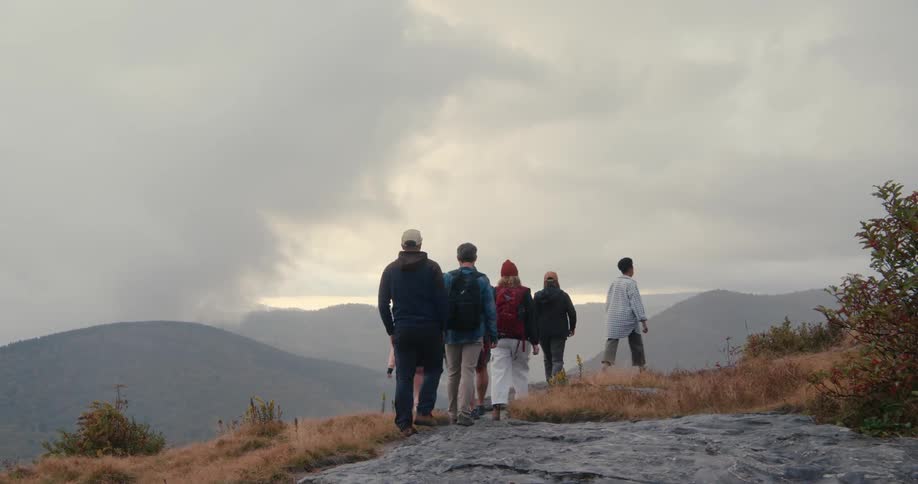 Friends on top of a hill watching the landscape at sunset