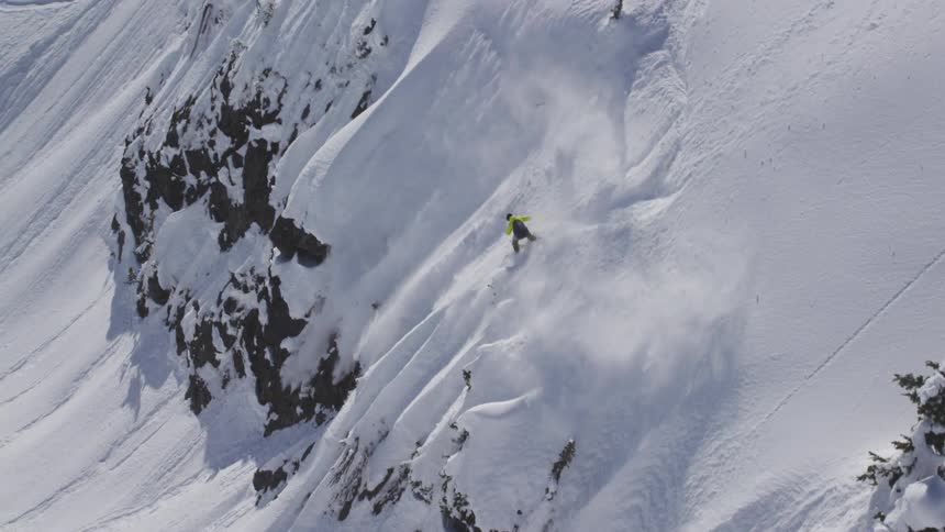 Aerial of snowboarder riding spines into powder in the backcountry
