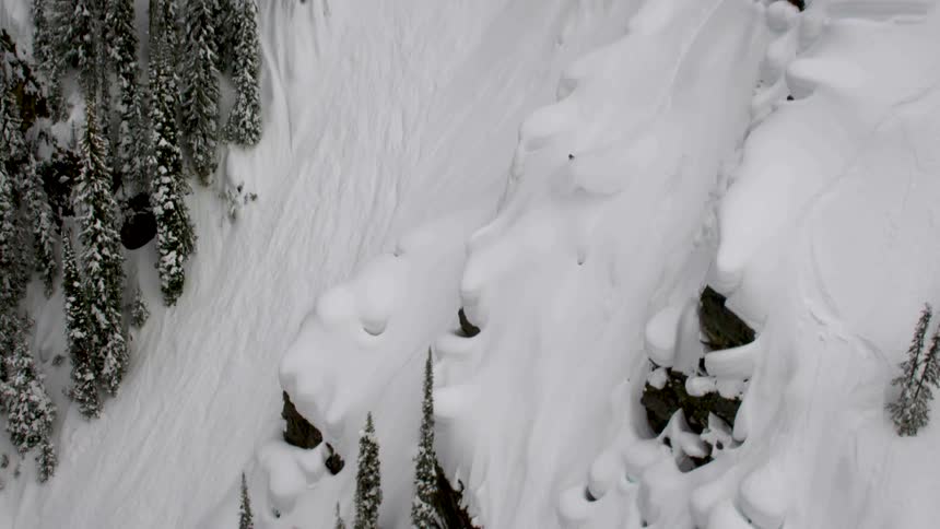 A person descending the snowy mountain on a snowboard during winter