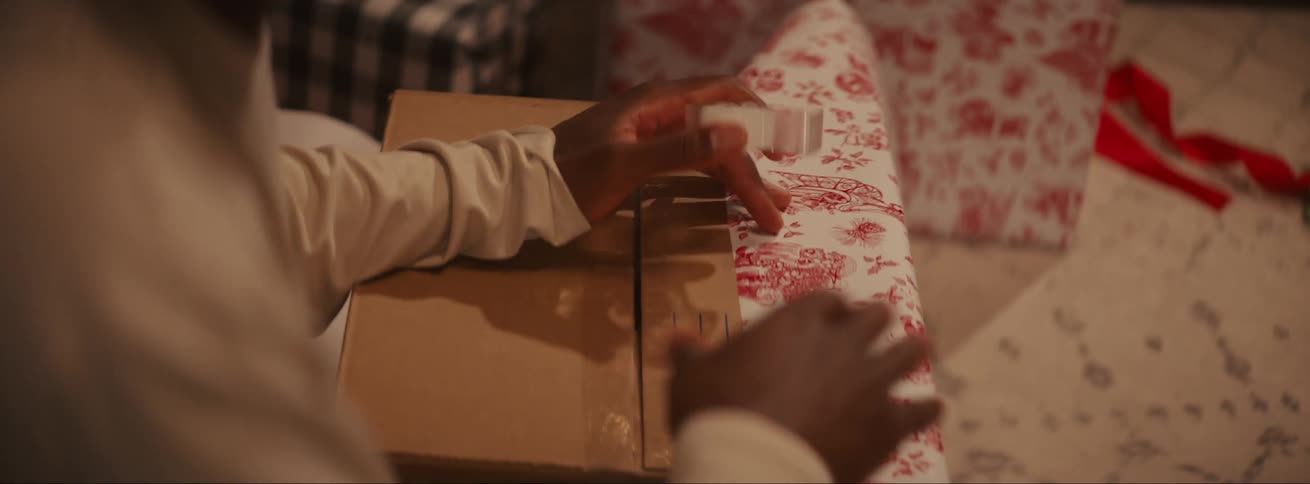 Hands of a person wrapping a gift with adhesive tape