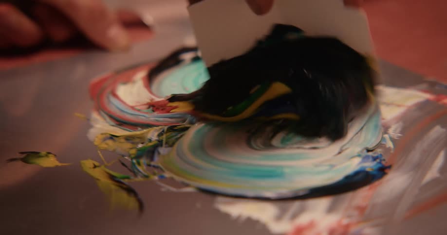 A human hand is mixing several colors of paint