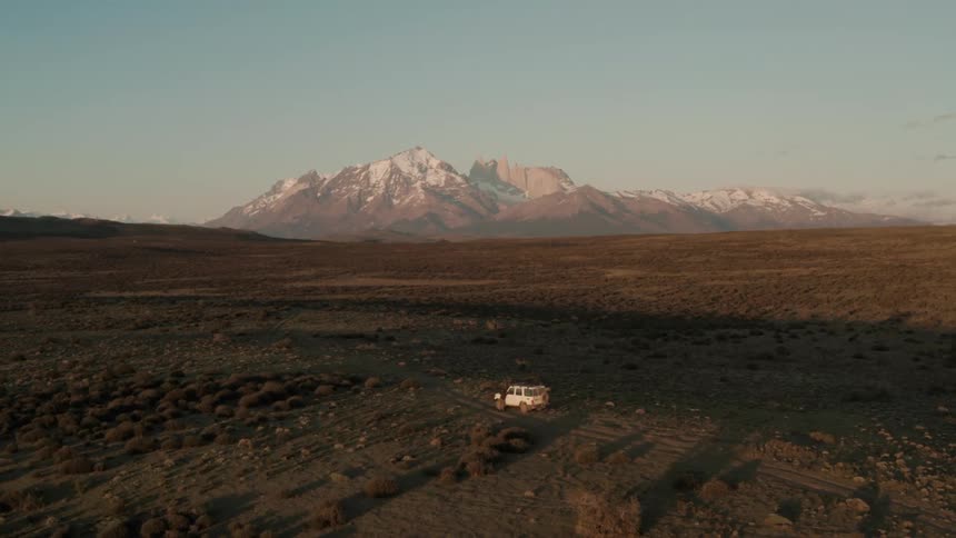 An aerial view of a dry plain with a large mountain in the distance at dusk