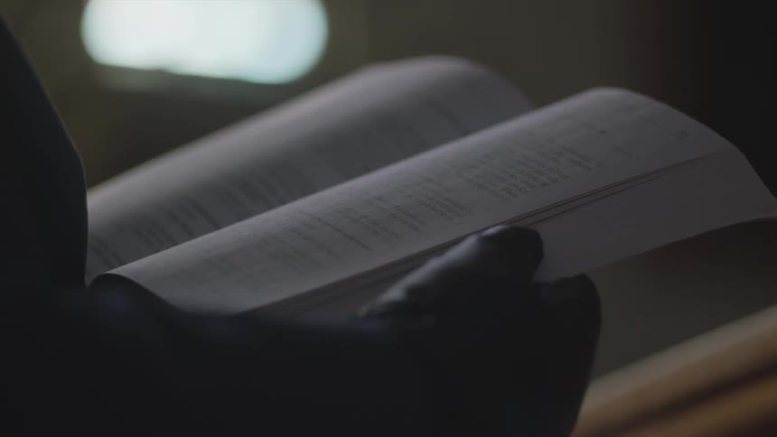 Hands of a person wearing gloves flipping through the pages of a book