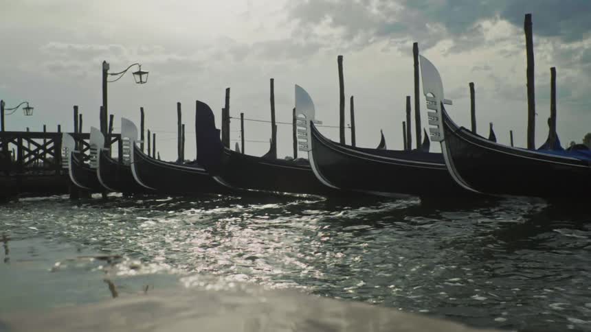Several identical boats parked on top of the water which is well moving