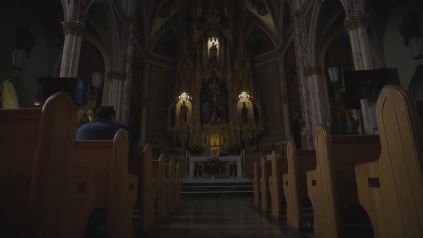 Man kneeling on a church pew facing the altar