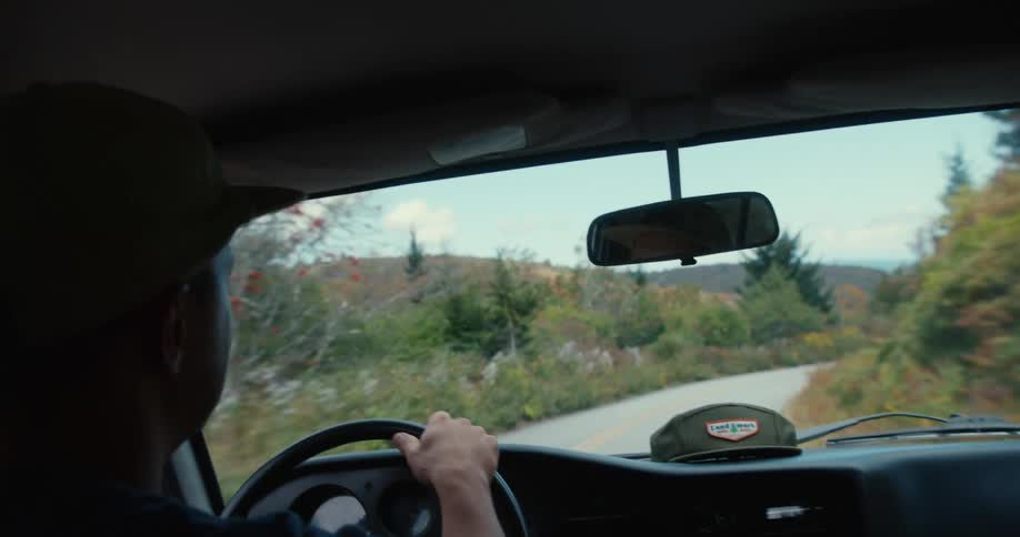 A man is driving a car on the small road