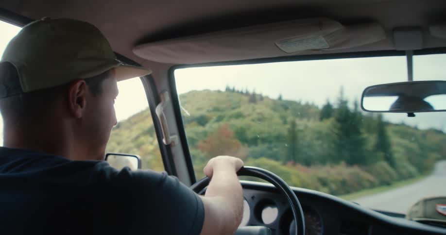 A man driving a car on the road during the day