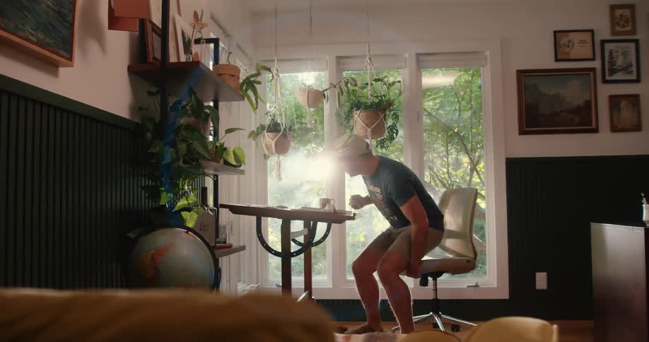 Man sits on a desk in his studio next to a garden