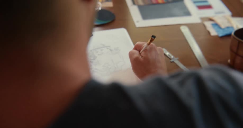 Artist draws on a notebook looking at color references