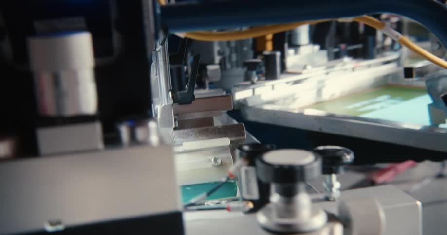 Screen printing machines running rollers over white shirts on a tray