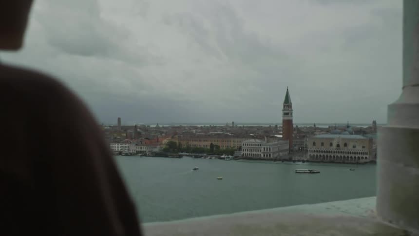 Balcony perspective of venice and the basilica by the sea under a clouded sky at dusk