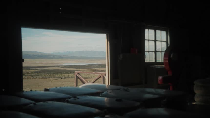 A view from inside a wooden cabin with the window open and overlooking the countryside