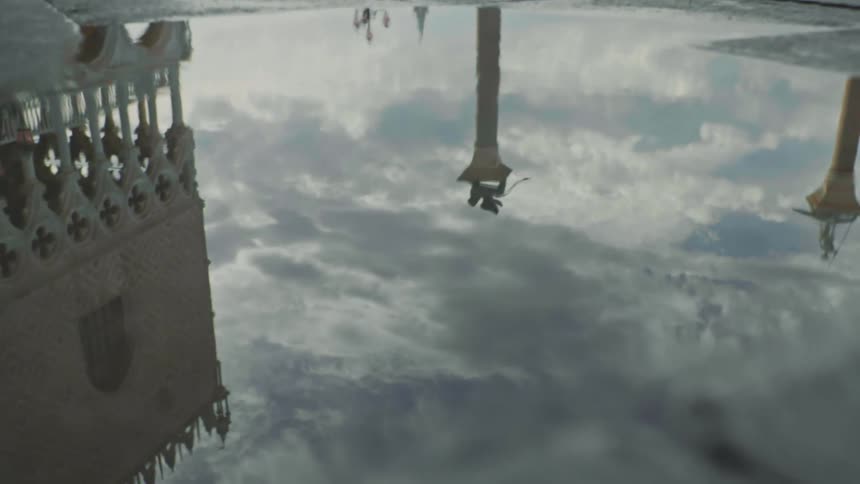 A puddle of water that reflects some buildings and the sky
