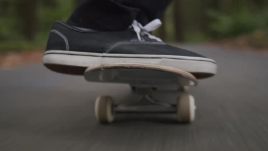 A person riding a skateboard on a street in the forest