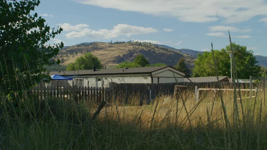 View of a natural field with residences and mountains on the horizon