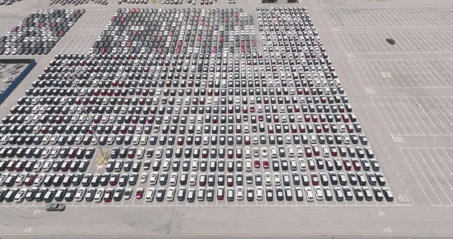 Huge parking lot filled with cars parked side by side on a sunny day