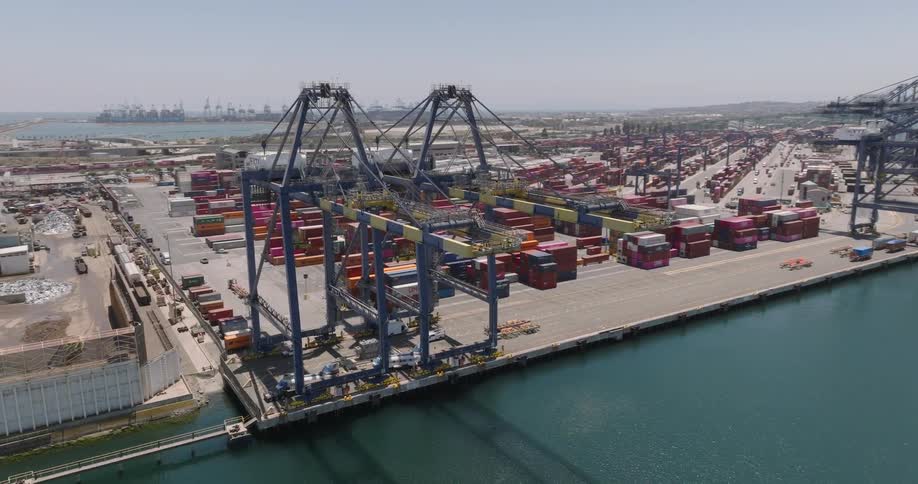 Loading cranes at extensive loading dock cast shadows onto water on a hazy day