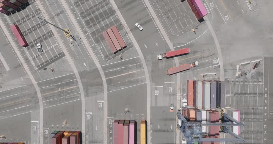 Some trucks carrying containers that are passing over an asphalt ground