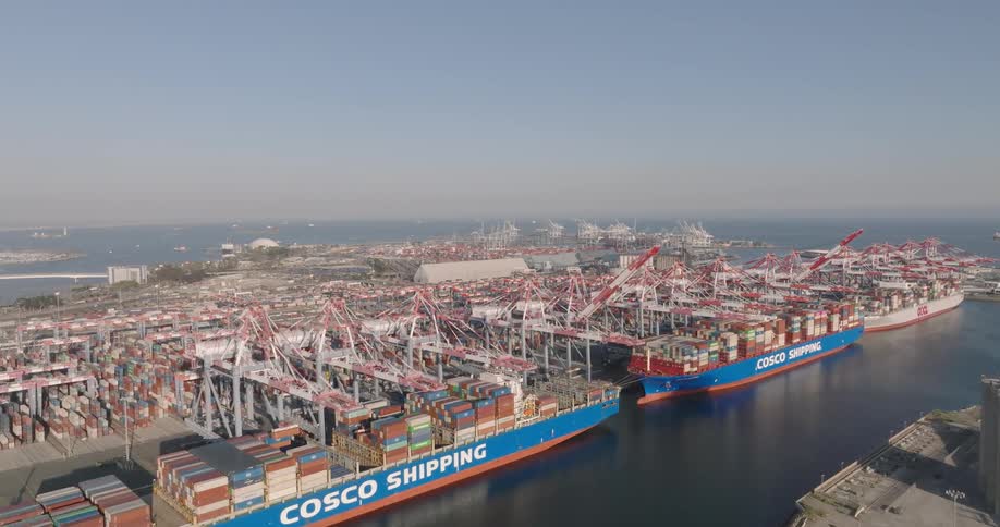 Container ships sit at loading docks in port on foggy day
