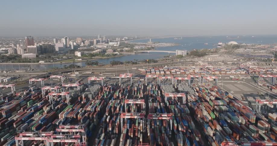 A region with many stacked containers and at the background there is a river and behind it a city