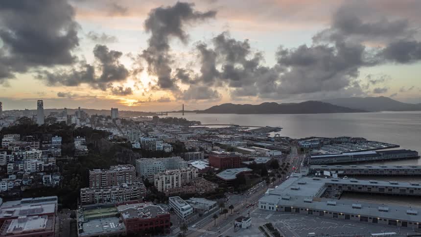 Aerial of port at the edge of a metropolis city at dawn and dusk under dark clouds