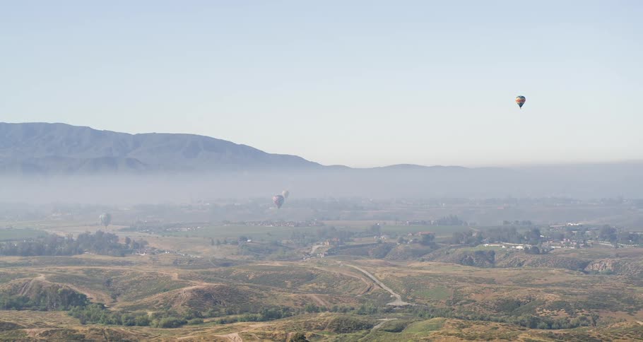 Hot air balloons flying over the rural landscape on a sunny day